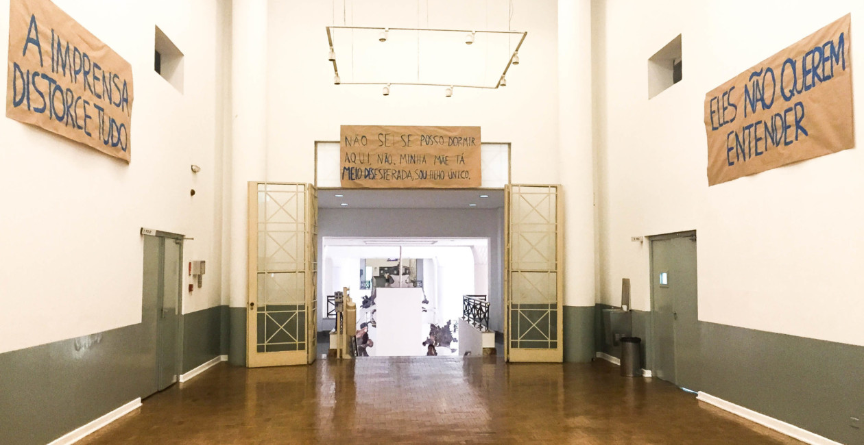 Corredor com grande porta aberta e frases escritas em papéis nas paredes