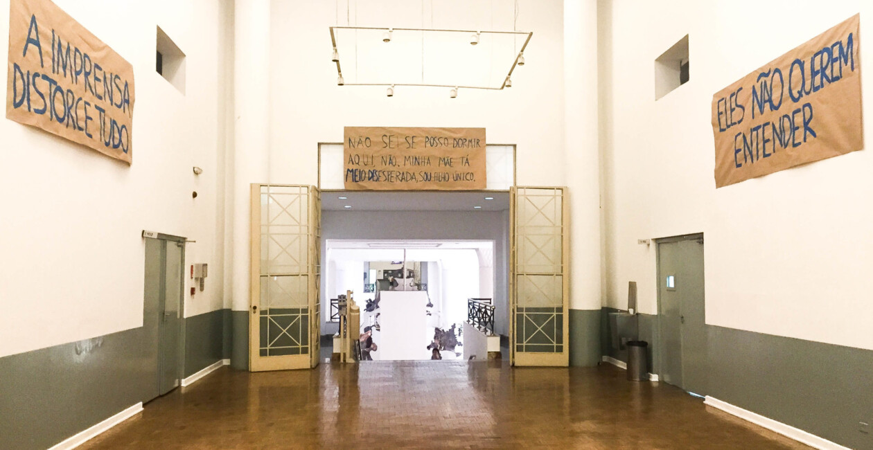 Corredor com grande porta aberta e frases escritas em papéis nas paredes
